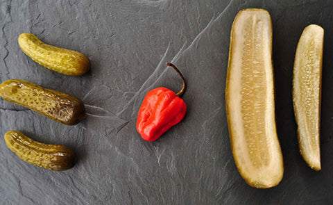 pickles on a slate board with a pepper