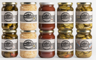 Assorted jars of McClure's pickles and sauerkraut on a white background