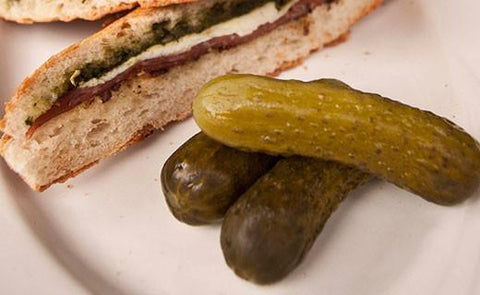 pickles on a plate next to a sandwich